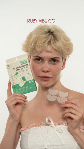 A model with short blonde hair holds the Ruby Vibe Co Blemishshield Max clear skin shields product