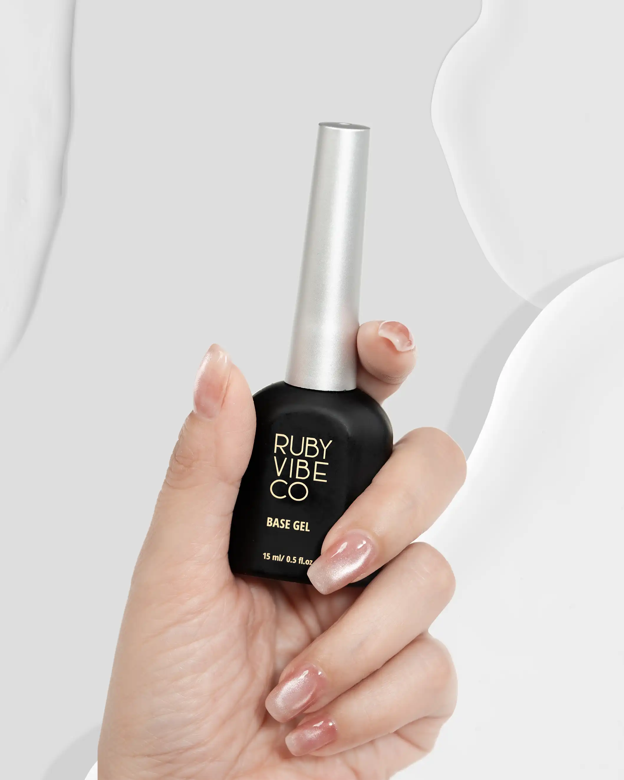 Lifestyle product photography of a hand modeling Ruby Vibe Co's Base Gel polish