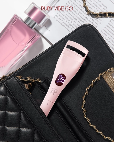 Promotional lifestyle photography showcasing a Ruby Vibe Co. heated eyelash curler in a handbag